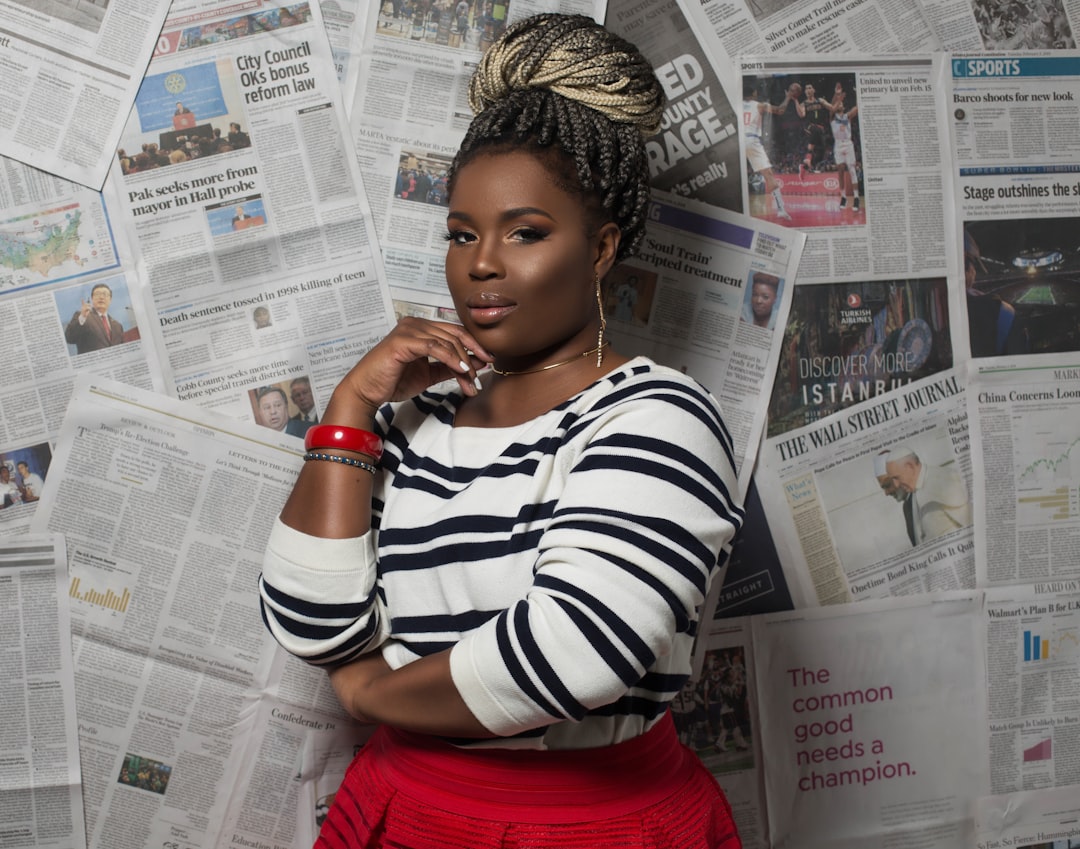 Woman with braided hair in striped shirt and red skirt.