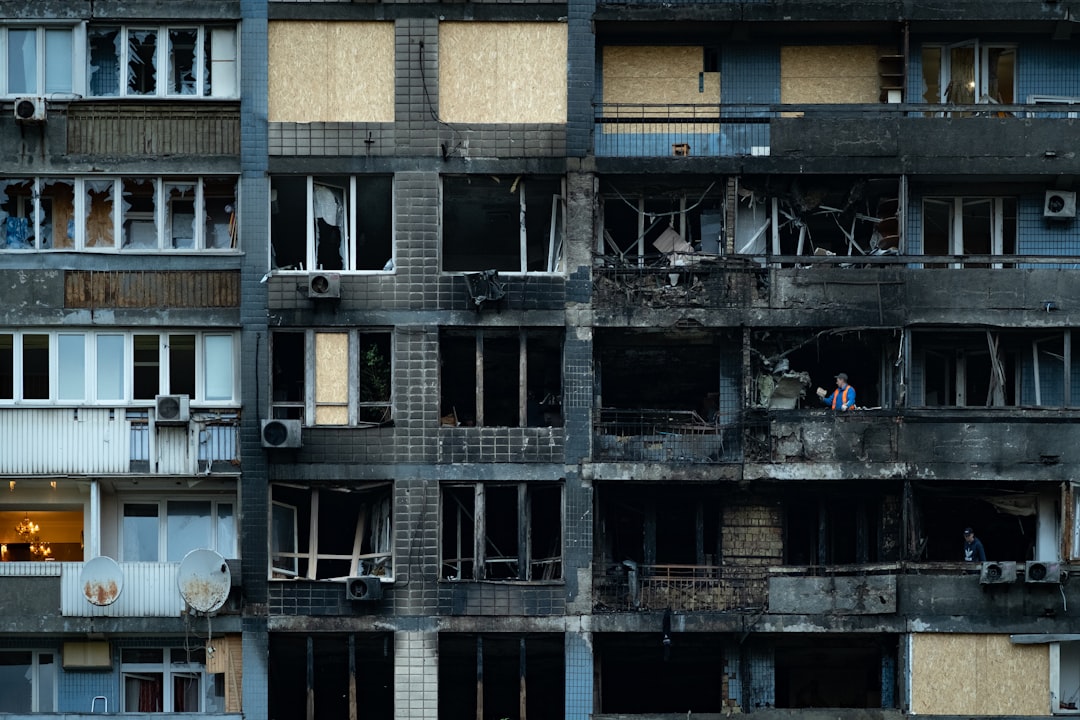 Damaged apartment building with burnt windows and sections.