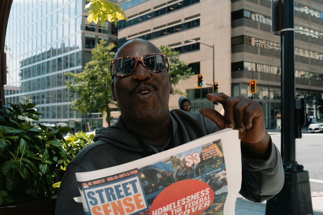 Man holds up "street sense" newspaper on city street
