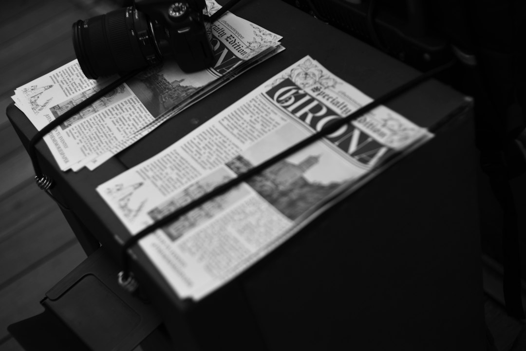 A camera resting on a newspaper with the headline Girona on a dark surface