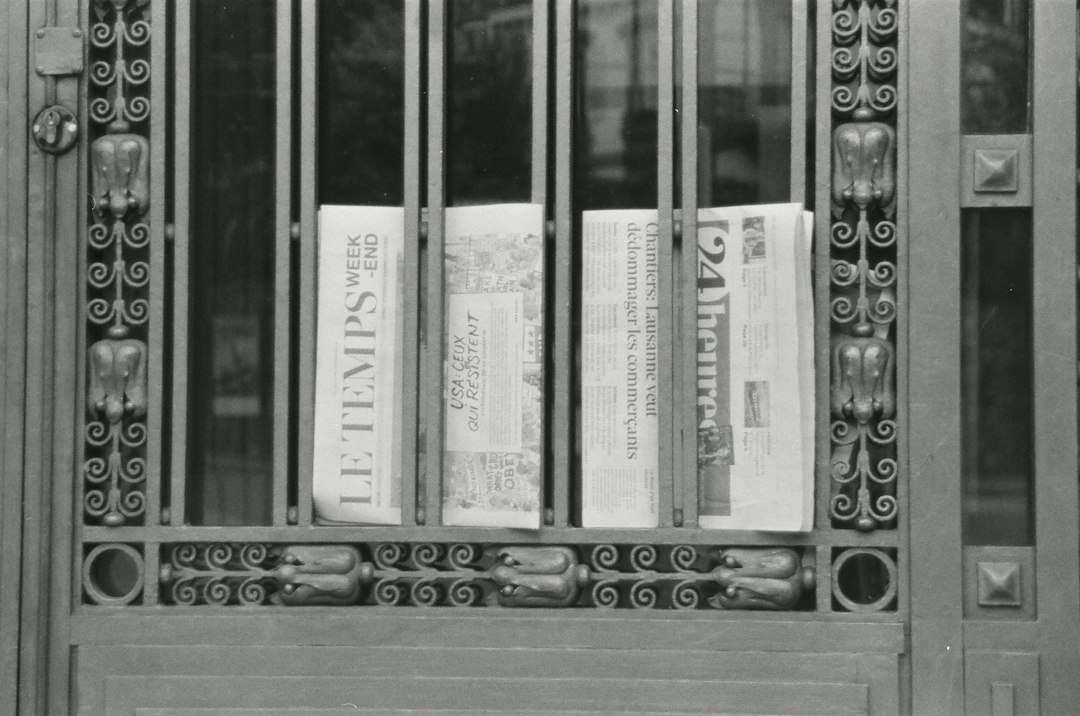 Newspapers behind ornate metal gate